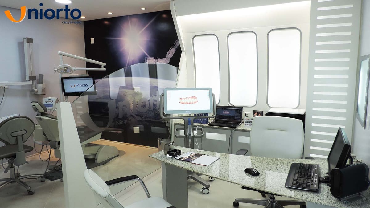 Sala de atendimento com cadeira odontológica e monitor exibindo o escaneamento 3D da arcada